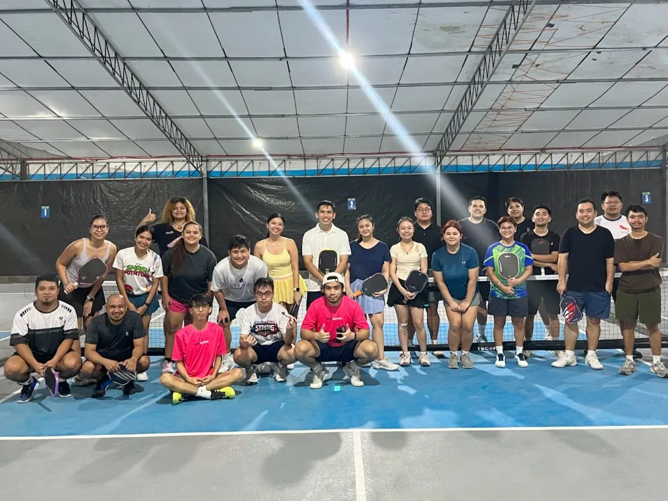 Pickleball group gathered on a blue indoor court