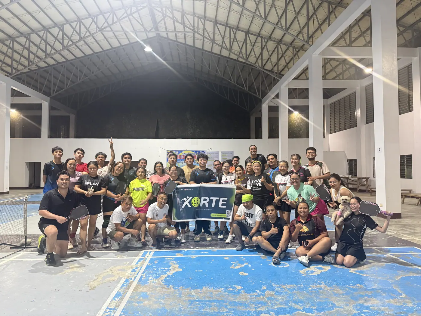 Pickleball players gathered behind a Korte banner after a game