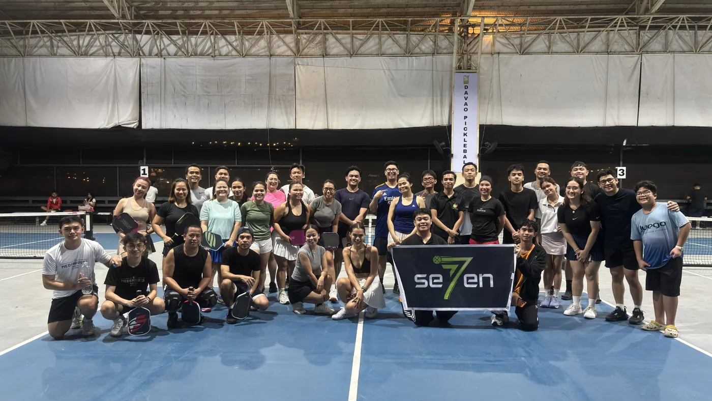 A large open play group gathered on a blue pickleball court